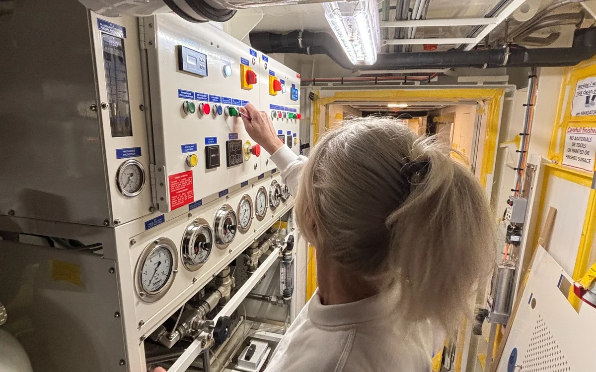 Onboard engineer operating equipment controls and examining pressure gauges