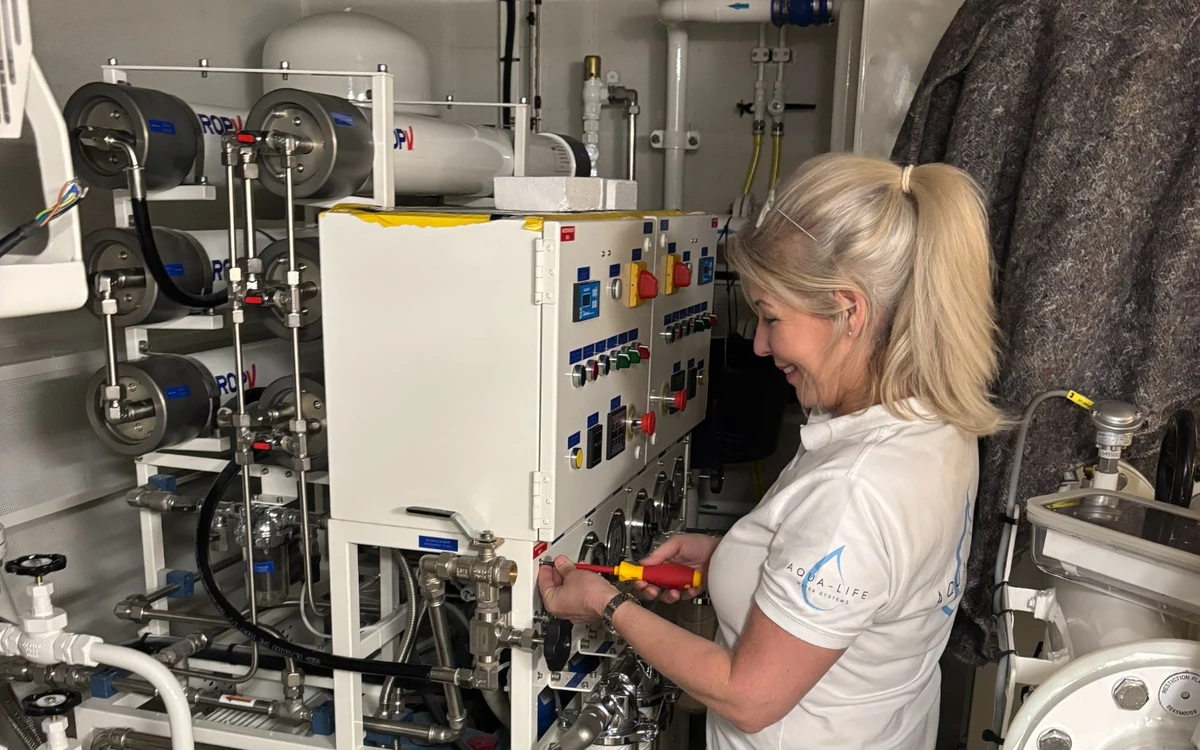 A crew member reviewing the control panel of a yacht water-treatment installation